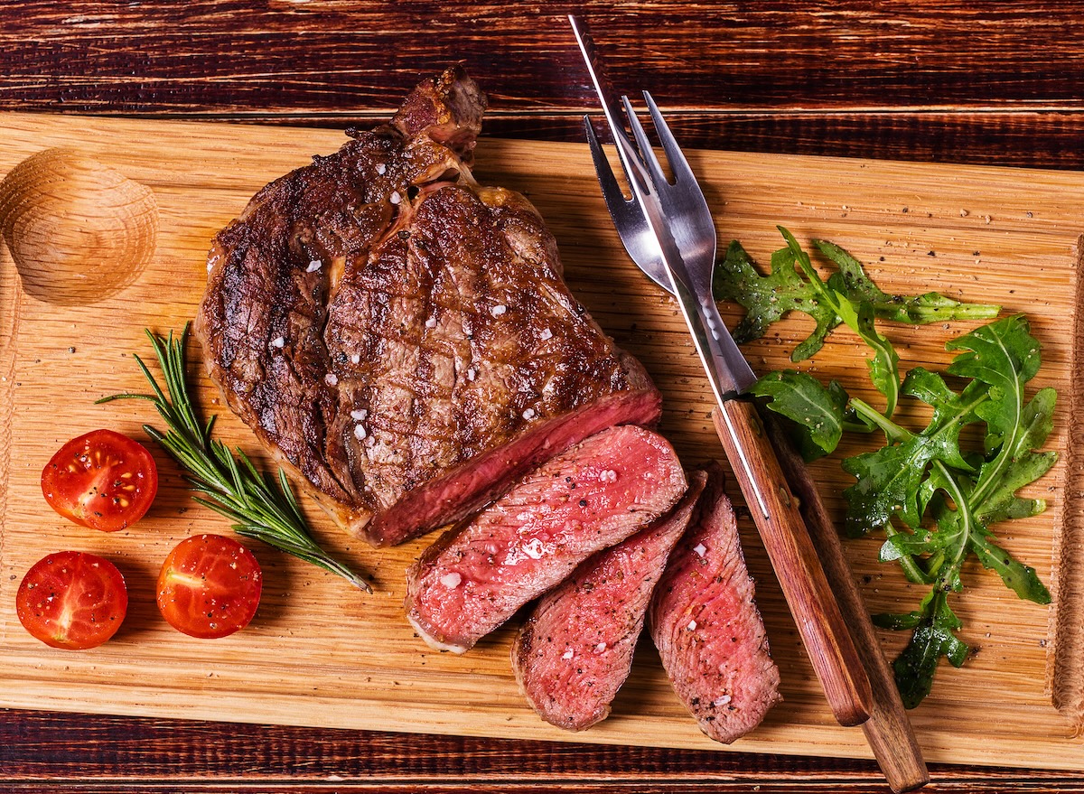Ribeye,Steak,With,Arugula,And,Tomatoes,On,Dark,Wooden,Background.