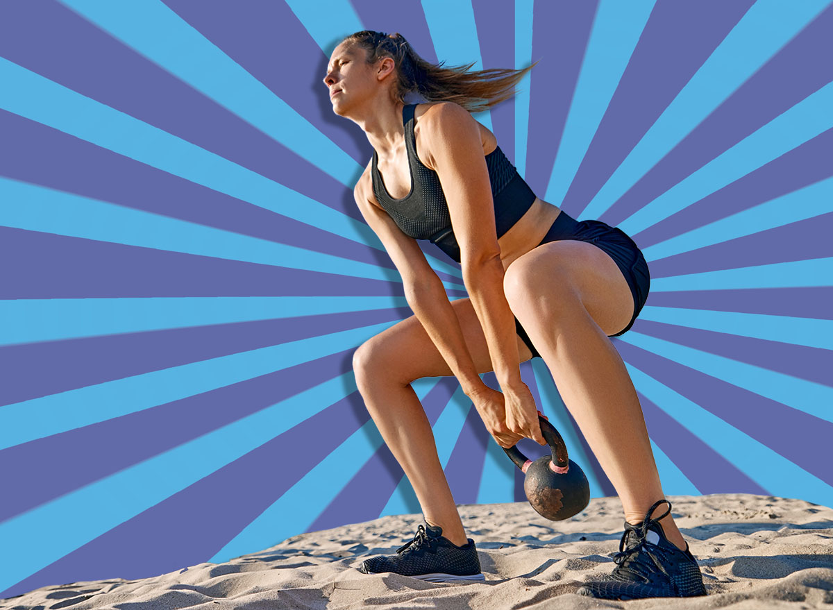 Man and woman with fit athletic bodies performing kettlebell swings on sandy beach, training against clear blue sky and water backdrop. Sport, active and healthy lifestyle, body care, fitness concept