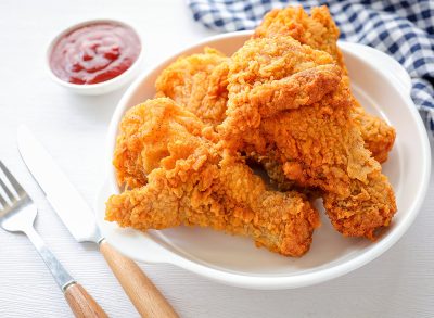 Fried crispy Chicken Drumsticks in white plate with tomato sauce on white background