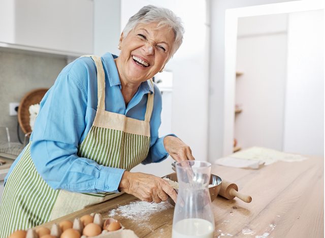 Portrait of a happy elderly womanhaving fun together preparing dough food in kitchen at home