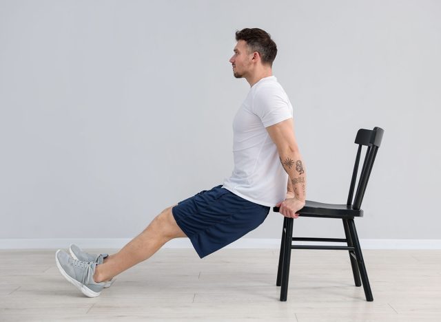 Handsome man exercising with chair at home