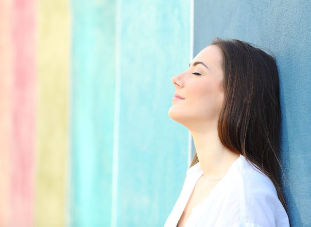 Side view portrait of a relaxed woman resting leaning on a colorful wall in the street