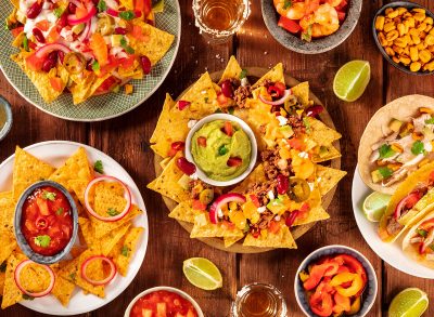 Mexican food variety, shot from the top on a rustic wooden background. Nachos, guacamole, tequila, tacos, a flat lay
