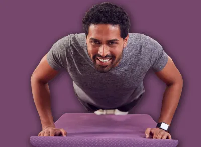 Man In Fitness Clothing At Home In Lounge Doing Press Ups And Exercising With Hand Weights