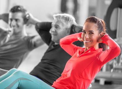Woman smiling at the camera while doing crunches in a group of various ages.