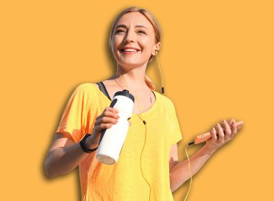 Sporty mature woman with bottle of water listening to music outdoors