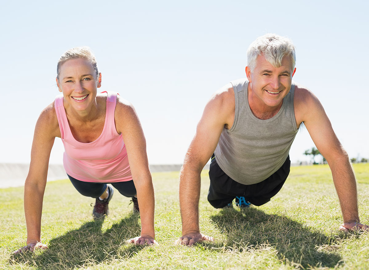 Fit mature couple warming up on the grass on a sunny day