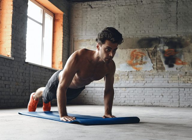Confident young man doing push-up exercises in gym