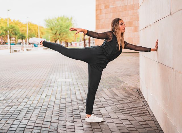 Slim woman doing yoga on street