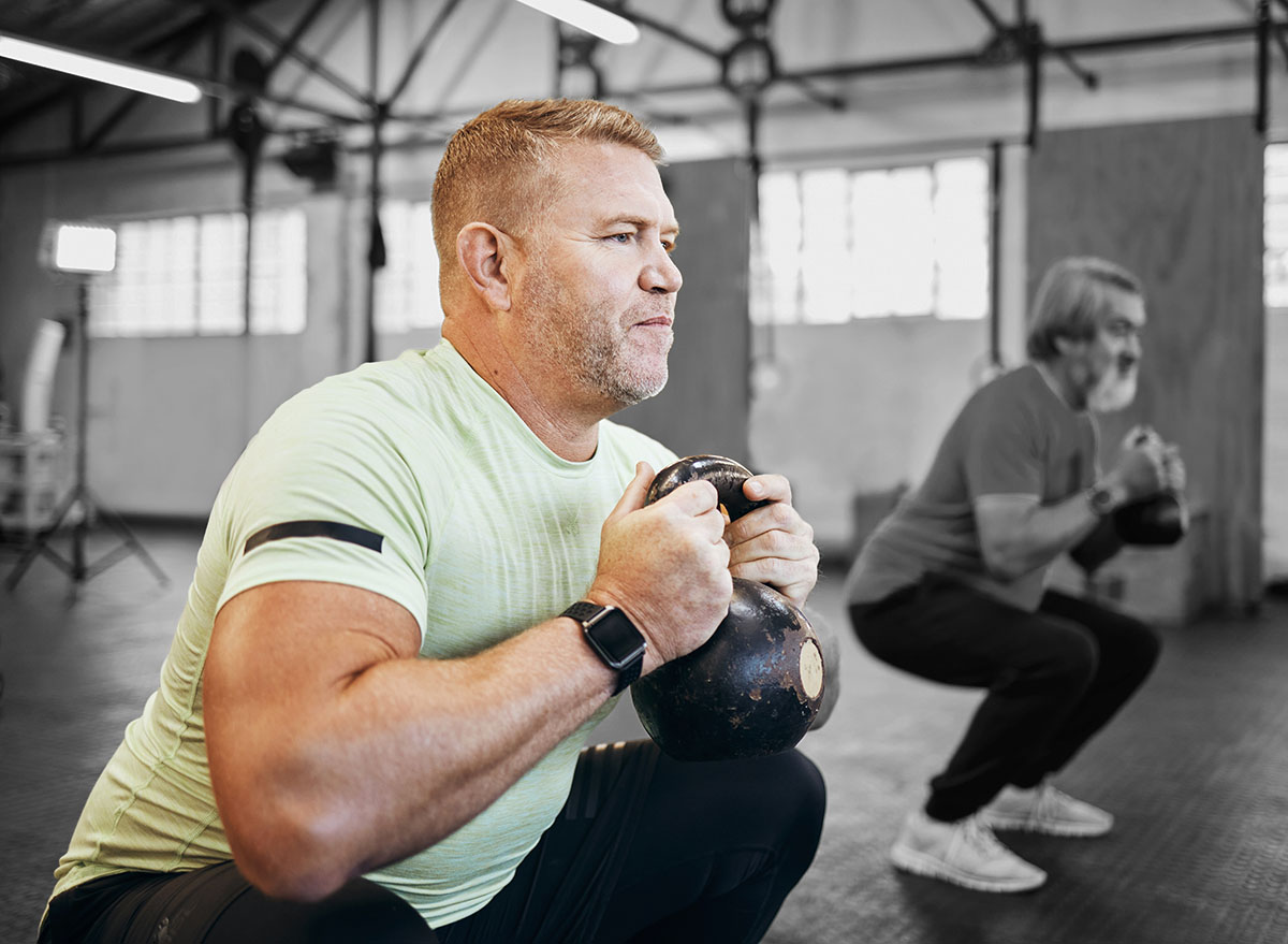 Men, exercise and gym with dumbbells for health and wellness for retirement fitness and energy. Senior or mature people class for squat workout or training for strong body muscle and goals motivation