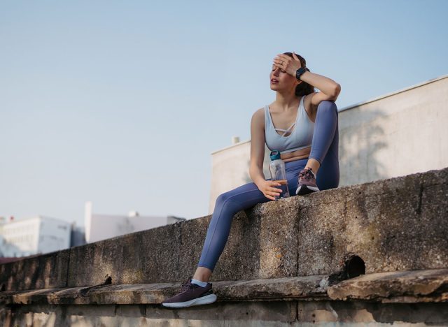 Young fitness woman resting after hard workout session on sunny morning.