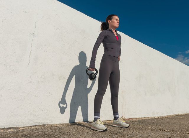 sporty woman holding a kettlebell weight, outdoors fitness concept