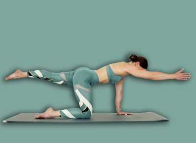 Fitness trainer performing the bird dog pose, balancing on hands and knees with extended arm and leg for core and stability training. Ideal for fitness routines