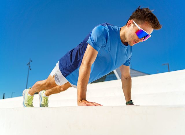 Fitness enthusiast performs push-ups outdoors on a sunny day in a modern training area