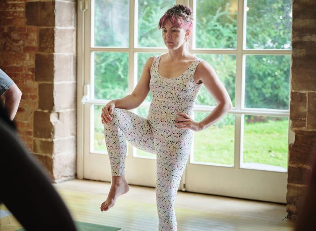 Yoga, woman stretching legs in class and exercise, fitness and healthy body, wellness or pilates. Knee to chest pose, person in gym and balance, practice and flexibility with calm or girl in studio