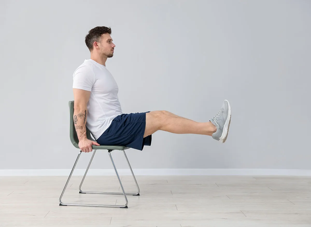 Handsome man exercising with chair at home