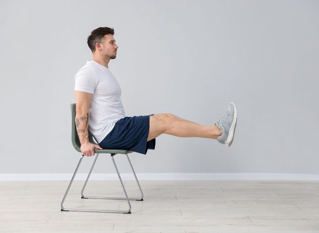 Handsome man exercising with chair at home