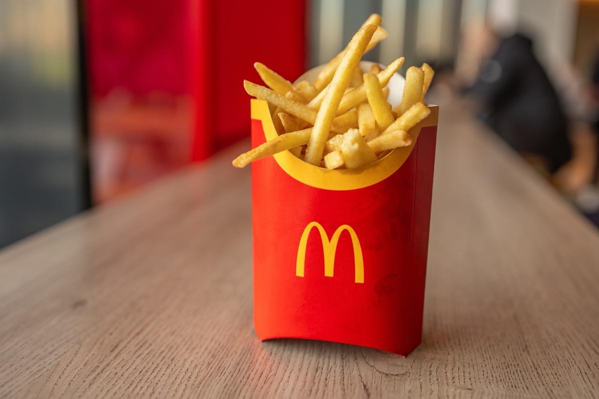Kyiv, Ukraine - January 31 2024: Close-up of a McDonald's french fries serving, in its classic red packaging, situated on a wooden table in a Kyiv outlet.