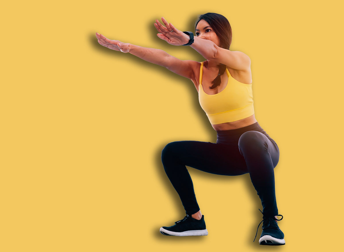 Side view of young attractive Asian fitness woman in sportswear doing deep squat at gym