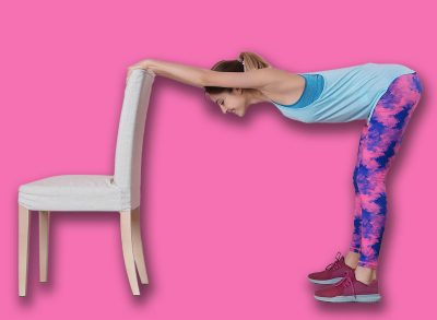 Young woman exercising with chair near color wall. Home fitness