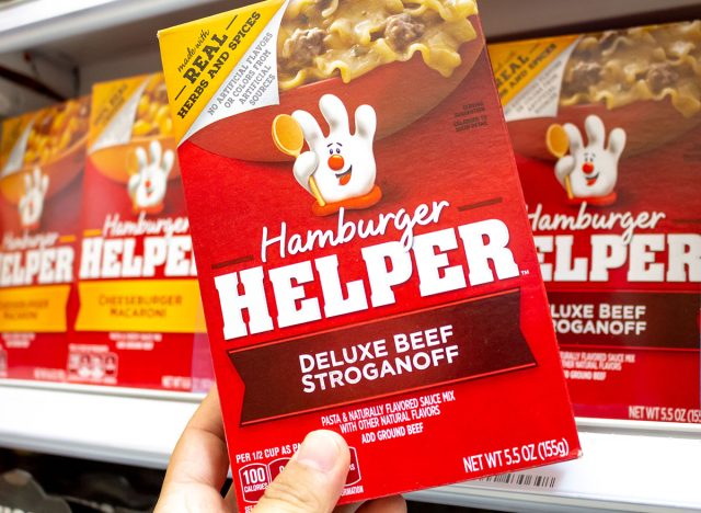 A view of a hand holding a box of Hamburger Helper at the grocery store.