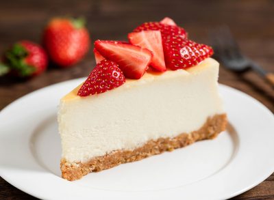 Cheesecake with strawberries on plate, wooden table