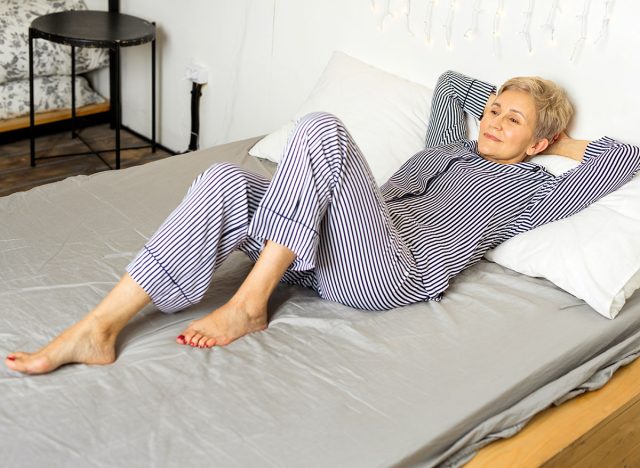beautiful elderly woman in pajamas lies on the bed