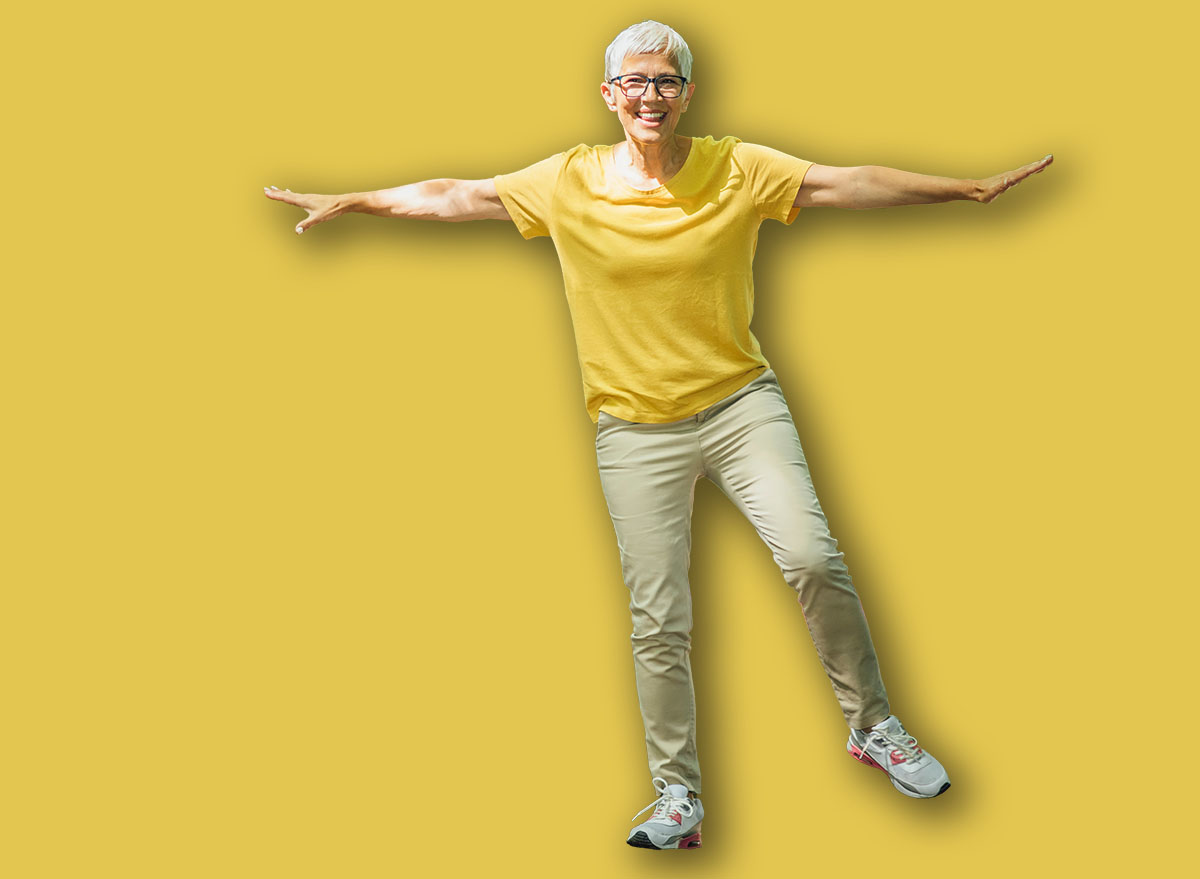 Balancing exercise outdoors. Mature woman standing on one leg, exercising balance