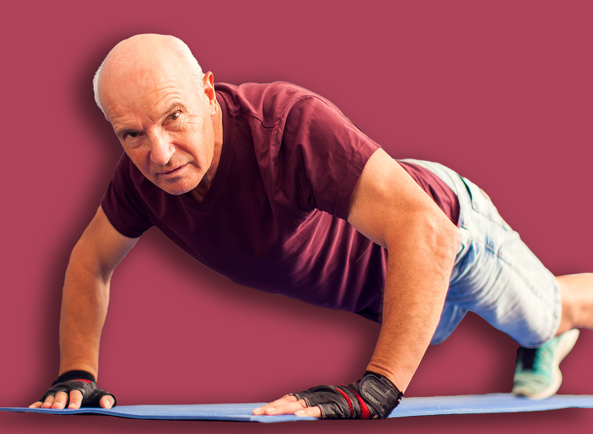 A portrait of bald senior man doing pushups exercise in the gym. People, healthcare and lifestyle concept