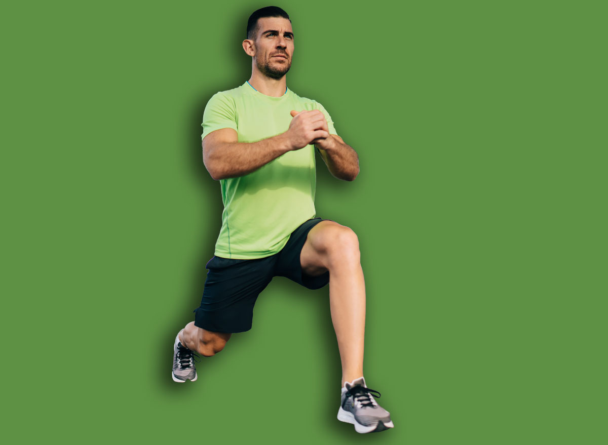 Full body handsome mature ethnic male in summer sportswear doing forward lunge on left leg with hands together while doing workout against contemporary geometric building