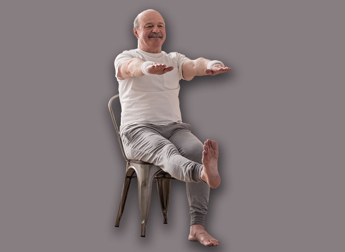 Elderly man practicing yoga asana or sport exercise for legs and hands on chair