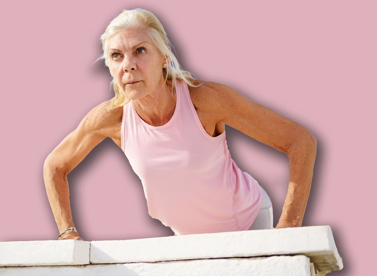 Mature woman working strength training push ups against sky with copyspace.