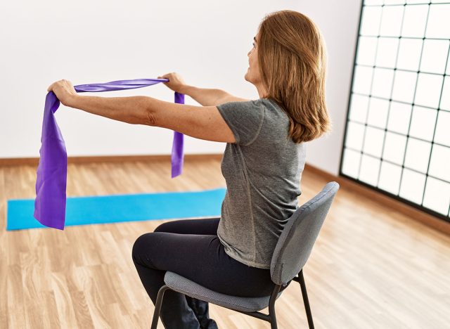 Middle age caucasian woman smiling confident training using elastic band at sport center