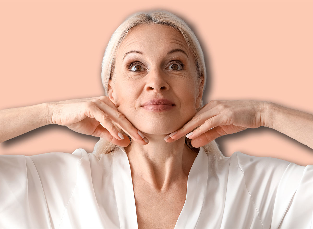 Mature woman doing face building exercise on light background