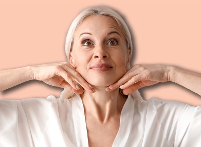 Mature woman doing face building exercise on light background