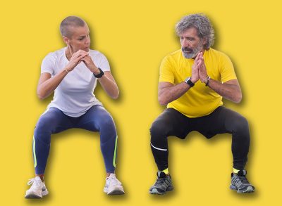 senior man doing a squat workout with his trainer