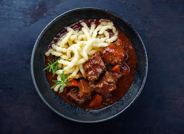 Traditional Hungarian braised venison goulash with vegetable and spaetzle in spicy sauce served as top view in a Nordic design bowl with 