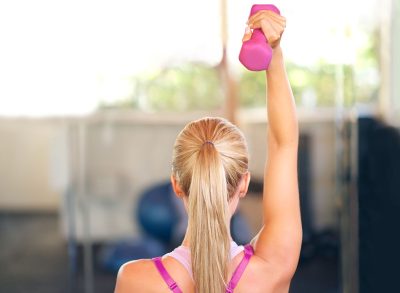 Exercise, workout and woman with dumbbell in gym for fitness, weightlifting and bodybuilding wellness. Female person, back and muscle with equipment for power training, arm strength and healthy body