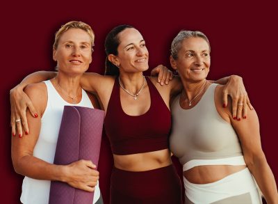 Three mature women enjoying a warm moment together on the beach. They are wearing activewear and radiate health and happiness, celebrating friendship before or after a yoga session by the ocean.