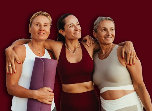 Three mature women enjoying a warm moment together on the beach. They are wearing activewear and radiate health and happiness, celebrating friendship before or after a yoga session by the ocean.
