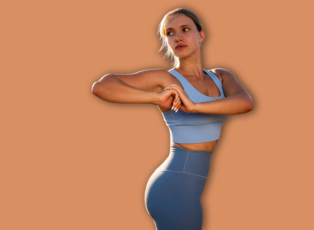 Woman exercising outdoors, fit athlete female in blue sportswear doing body twist exercise, warming up before running in mountains at sunset, sport activities in nature, healthy lifestyle, portrait