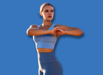 Woman exercising outdoors in mountains at golden hour sunrise, fit female athlete doing body twist exercise in blue sportswear, warming up before trail running in nature, portrait