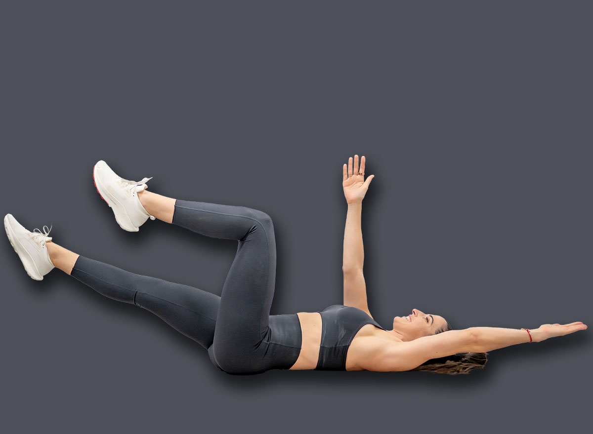 Woman performing dead bug exercise lowering opposite arm and leg for functional core training