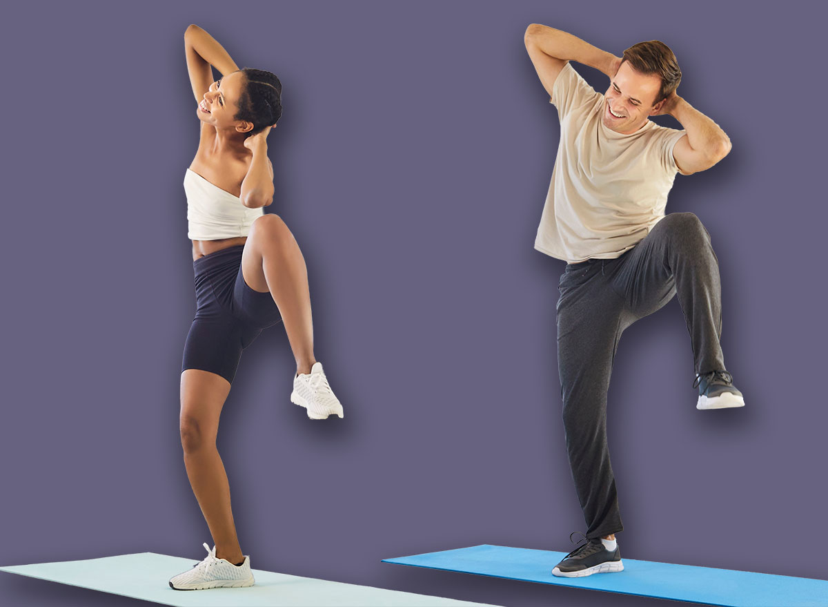 Happy couple doing home fitness workout together. Young fit woman and man perform exercise lifting knees up and to side with arms folded above head, two smiling active people training indoors