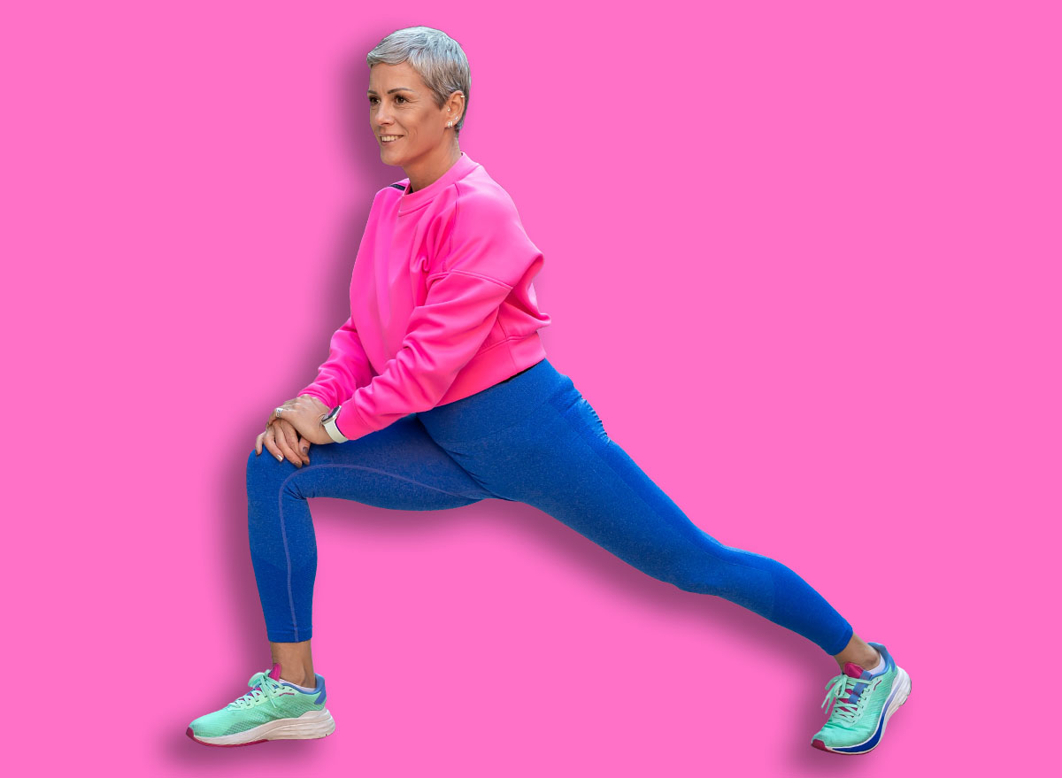 Gen z woman with short grey hair doing a lunge stretch outdoors on urban steps, smiling and focused during a fitness routine that promotes active, healthy modern living