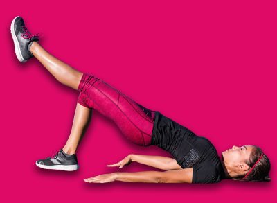 Fitness woman doing bodyweight glute single leg floor bridge lift exercices. Fit Asian woman exercising glutes muscles with one-legged floor bridge butt raise during summer in outdoor gym on grass.