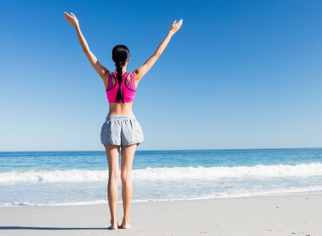 Woman with hands up on the beach on a sunny day