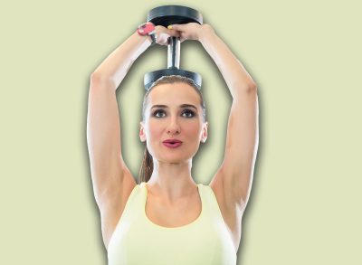 Portrait of a beautiful fit woman with can do attitude exercising triceps extension with dumbbell during workout in a modern fitness club