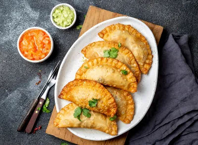 Latin American fried empanadas with tomato and avocado sauces. Top view.