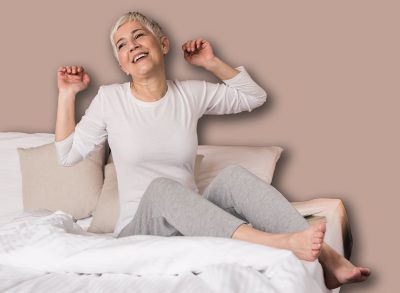 Lovely cheerful mature woman waking up and stretching in her modern bright apartment, Morning and begining of a new day concept